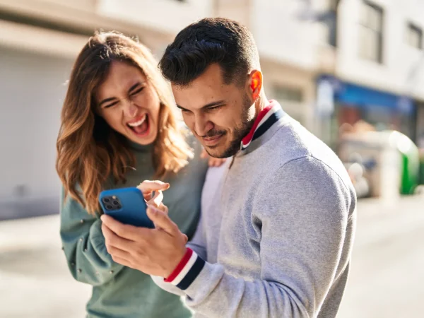 man-woman-smiling-confident-using-smartphone-street